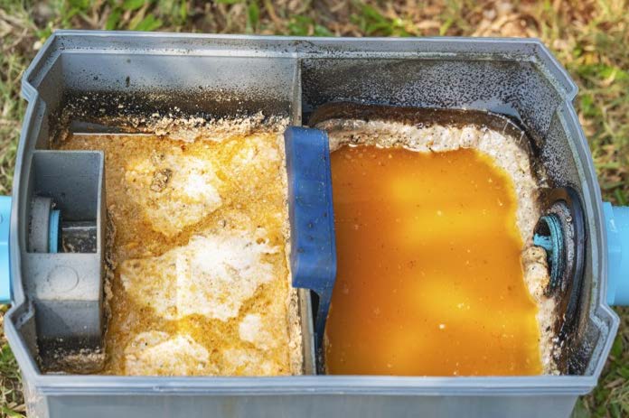 Top view of a grease trap interceptor filled with oily wastewater and solidified grease.